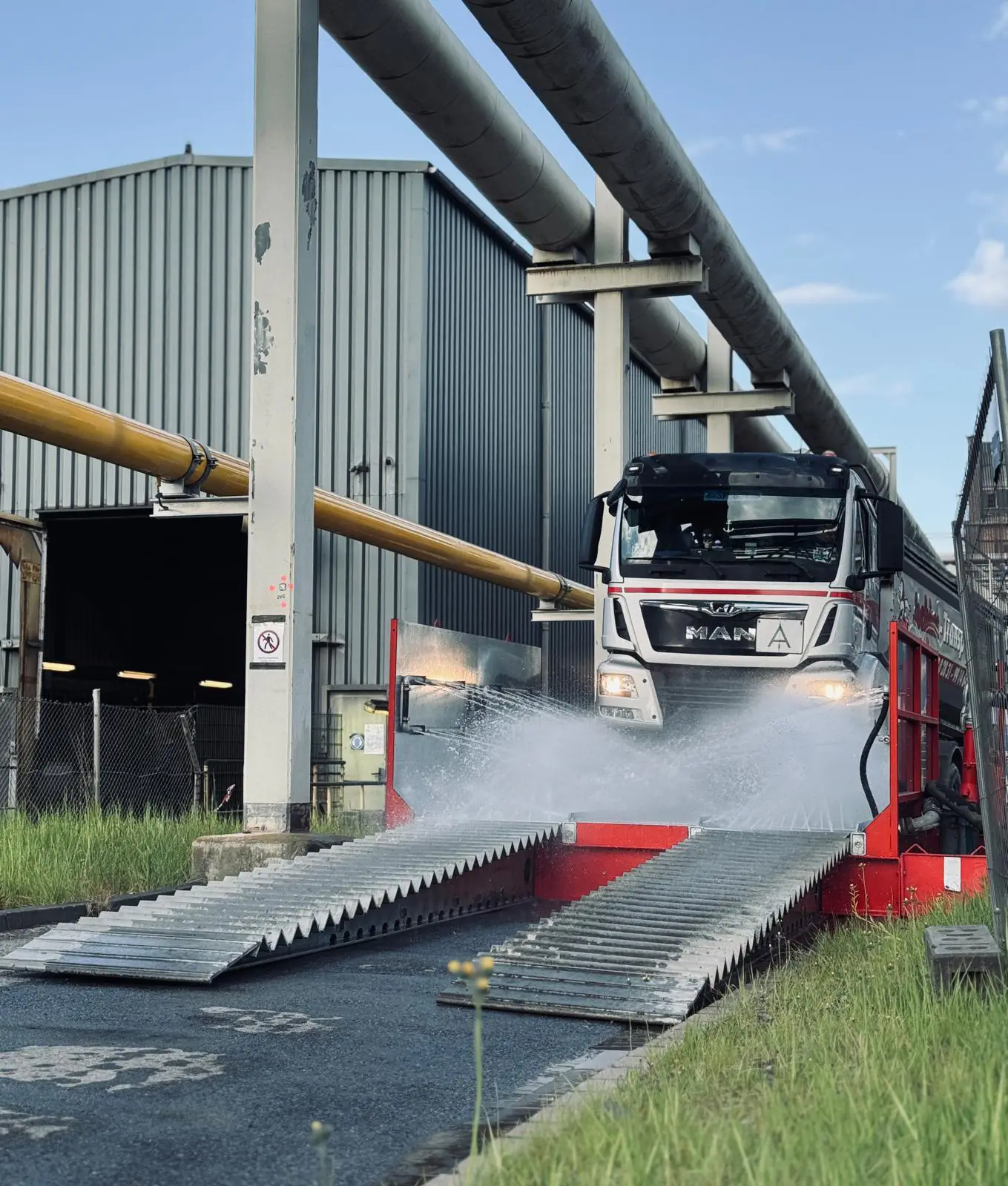 LKW fährt durch eine Reifenwaschanlage mit aktivem Wasserstrahl