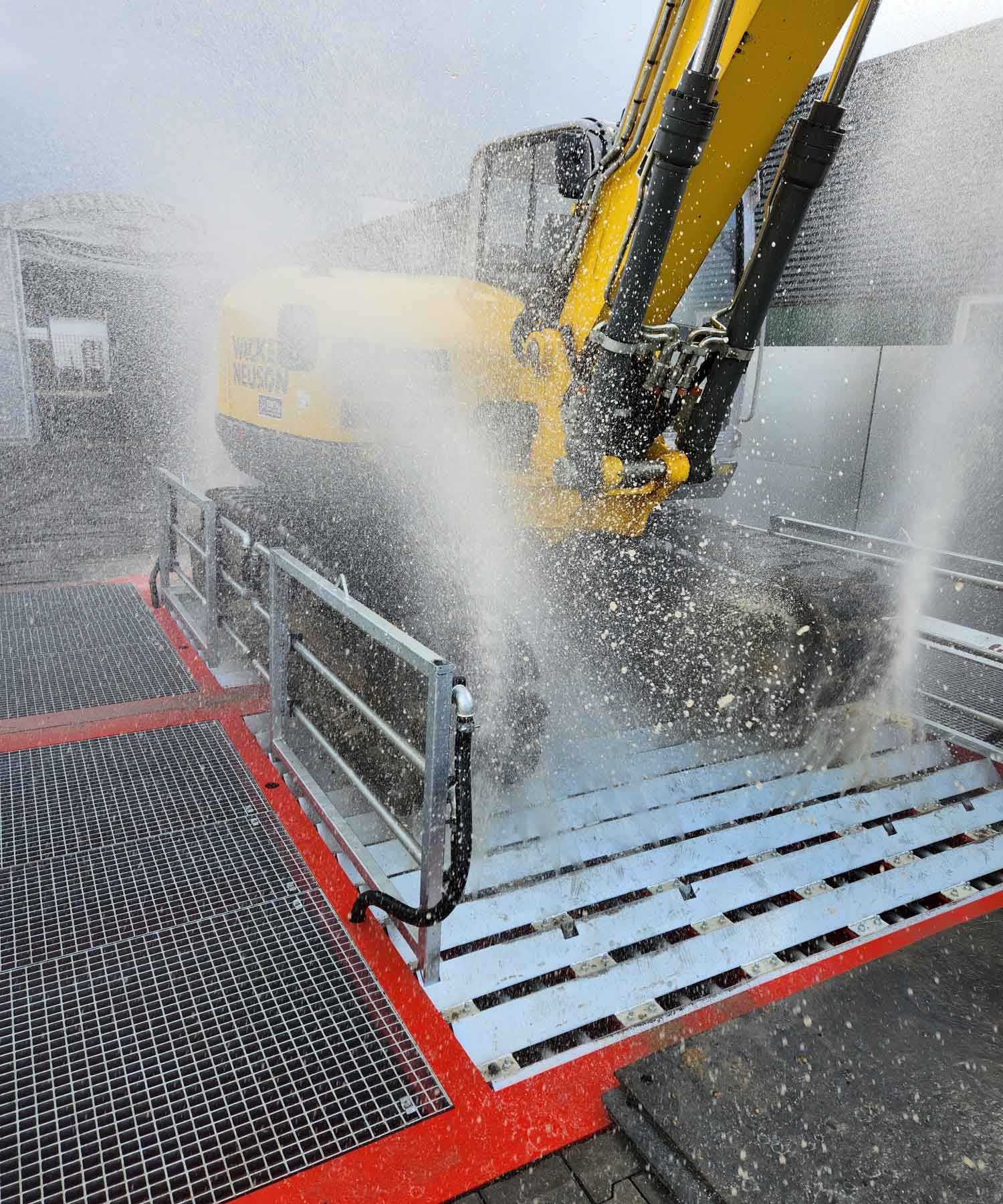 Bagger fährt über Demucking-Anlage mit Wasserstrahl von unten