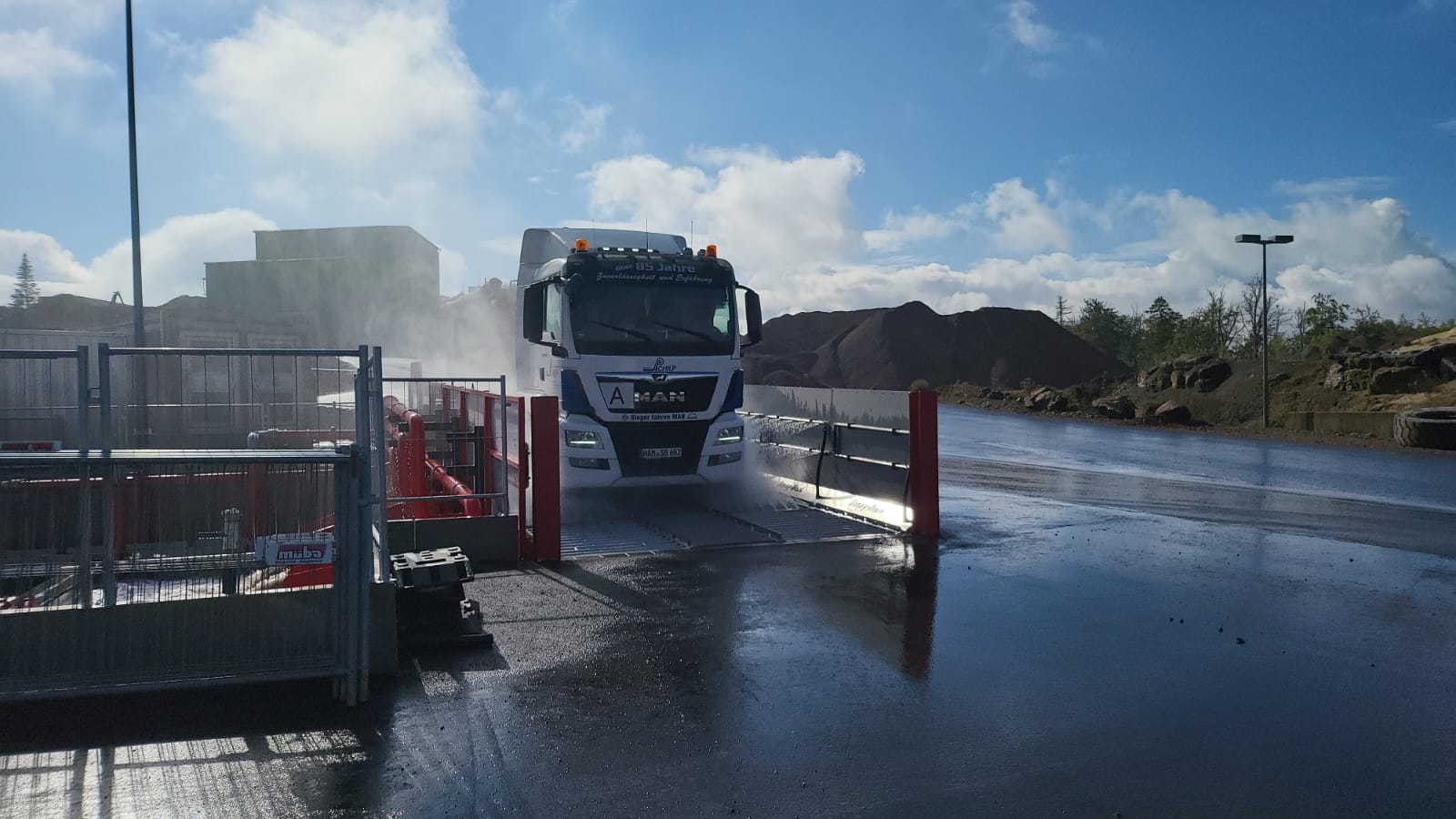 LKW fährt auf einem Platz durch die Reifenwaschanlage mit Wasserstrahl