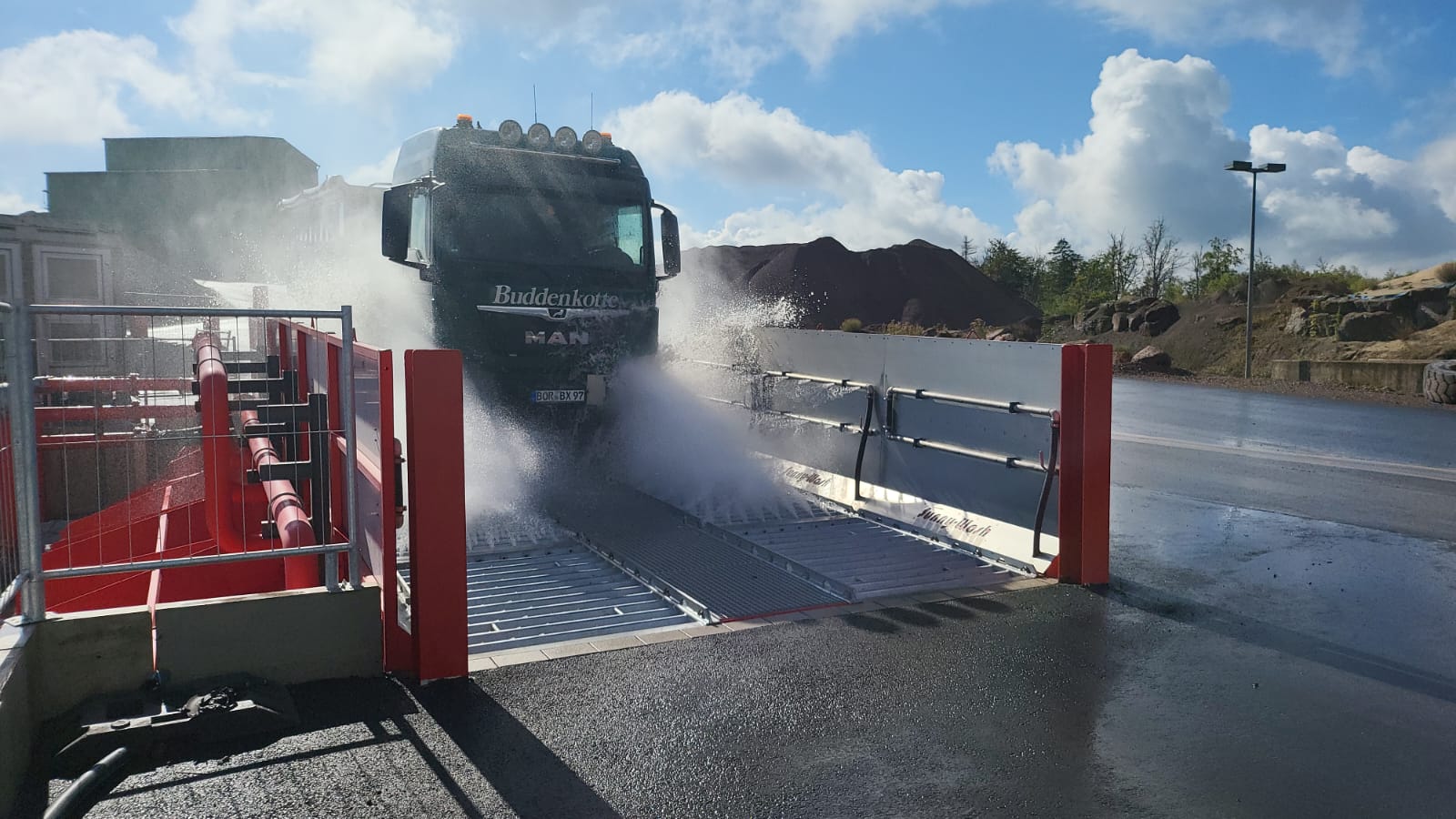 LKW fährt durch die Reifenwaschanlage einer Baustelle