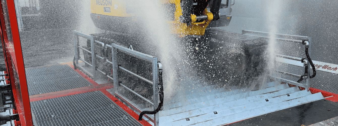 Bagger fährt über Demucking-Anlage, um Schmutz der Baustelle zu entfernen